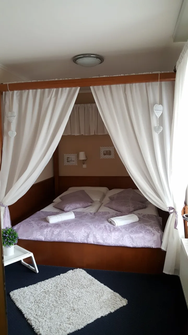 Espacio representativo del hotel: Un dormitorio con una cama doble enmarcada por cortinas blancas.