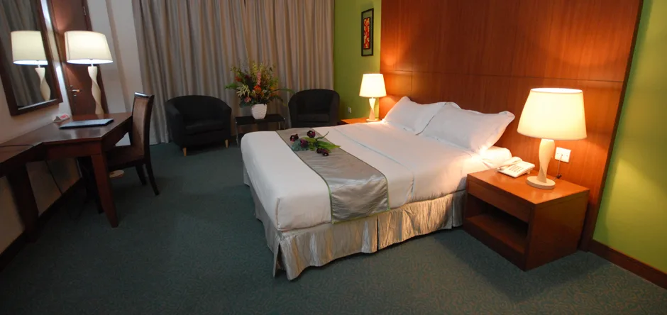 Espacio representativo del hotel: Un dormitorio de hotel con una cama bien arreglada y lámparas de noche.