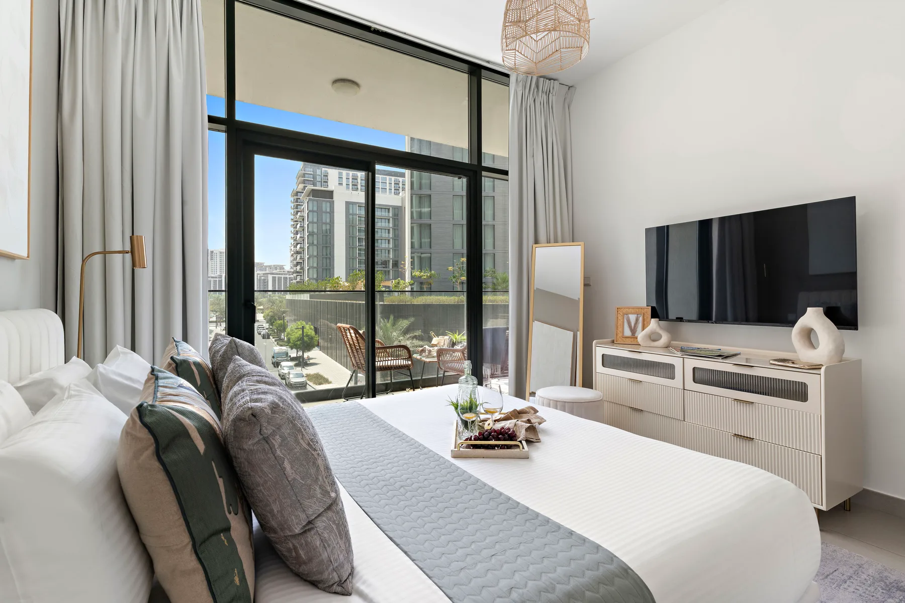 A bright bedroom with a bed, large windows, and a television.
