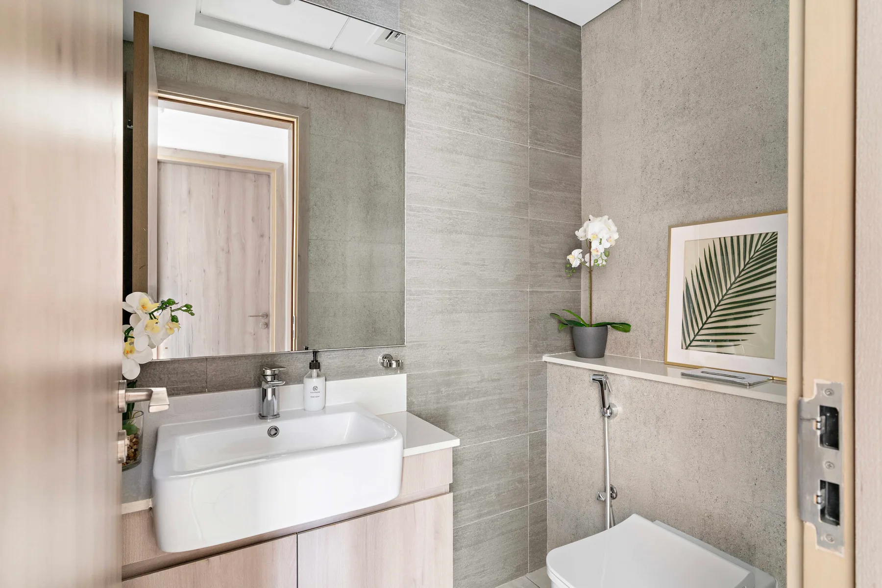 A bathroom with a sink, mirror, and partially visible toilet.