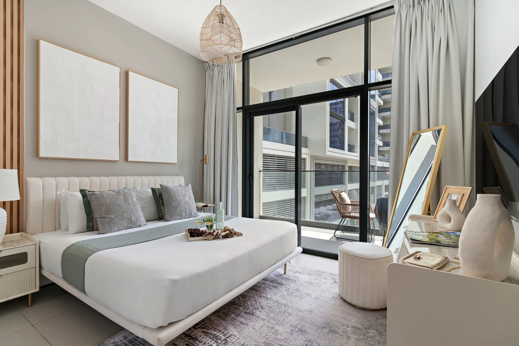A bright bedroom with a large bed beside floor-to-ceiling windows.