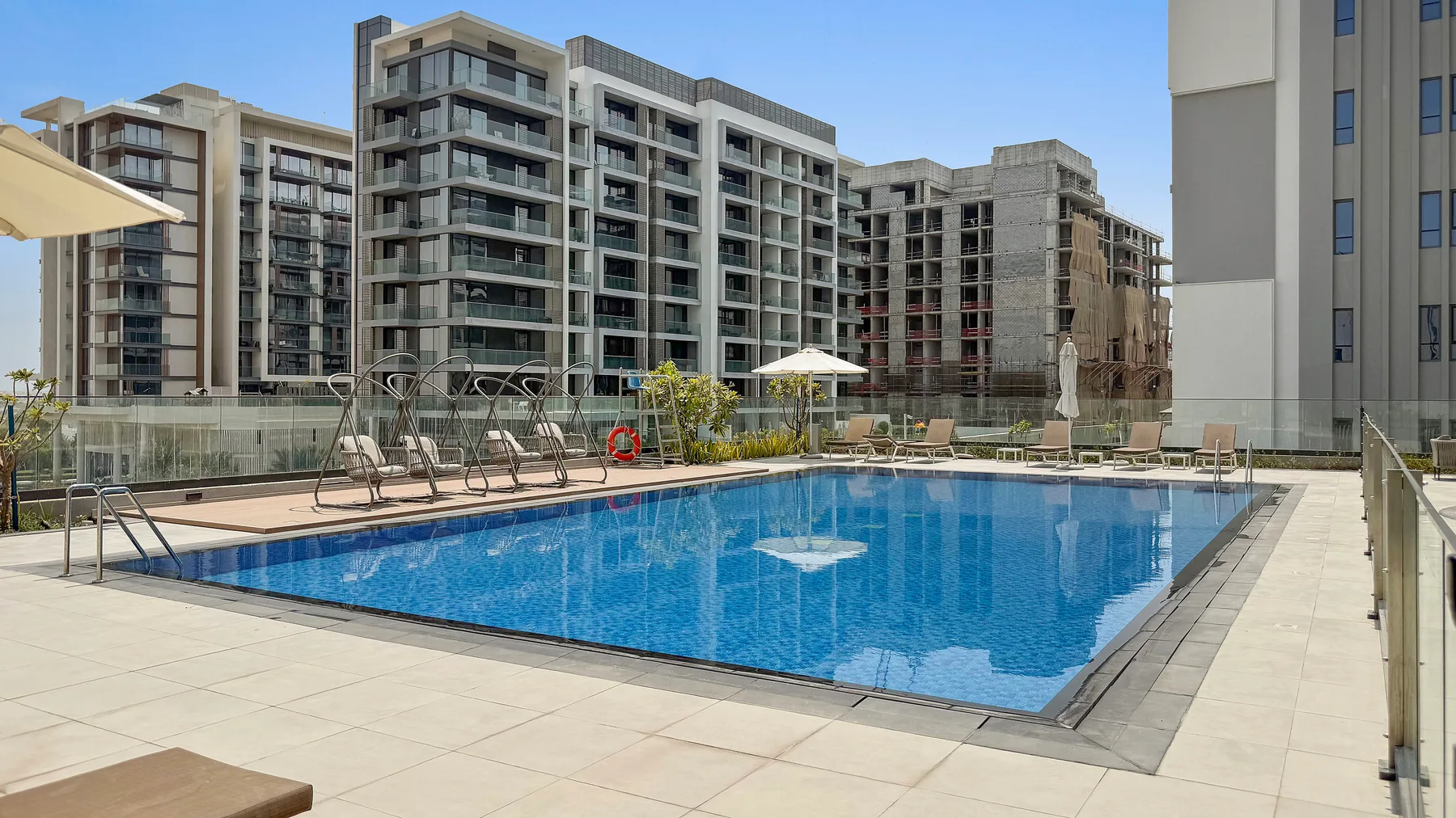Shared amenity: An outdoor swimming pool sits on a paved terrace among modern buildings.