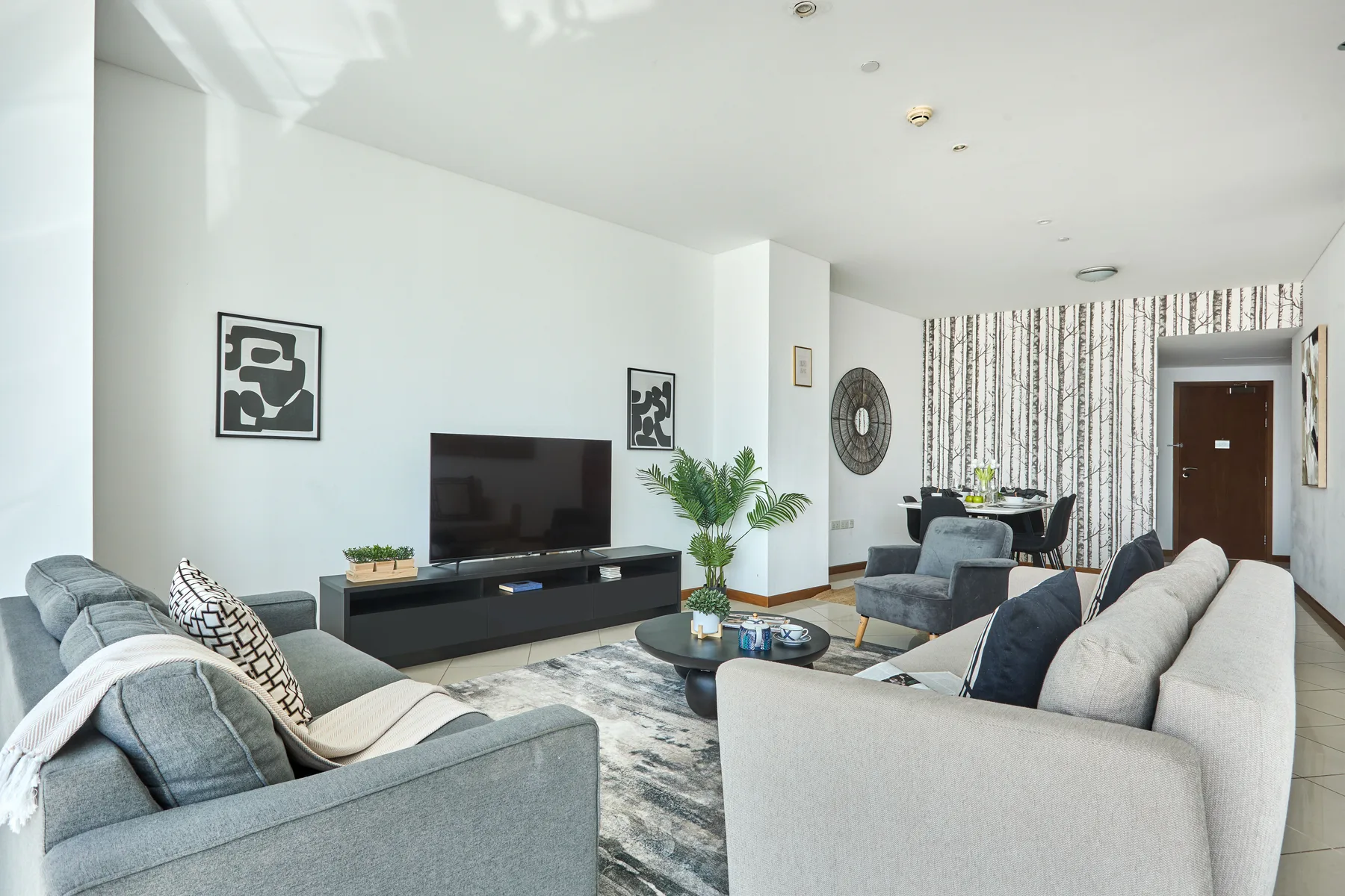 Una sala luminosa con sofás, un televisor y un comedor.
