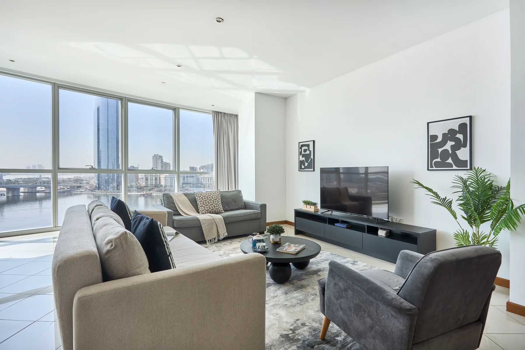 Una sala luminosa con asientos, un televisor y grandes ventanas con vistas al agua.