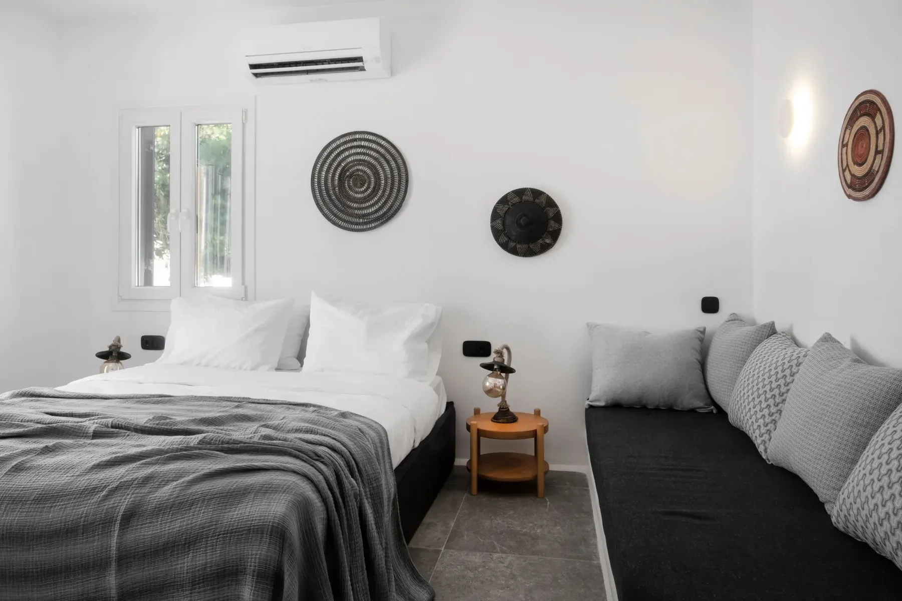 A bright bedroom with a bed and a cushioned seating area.