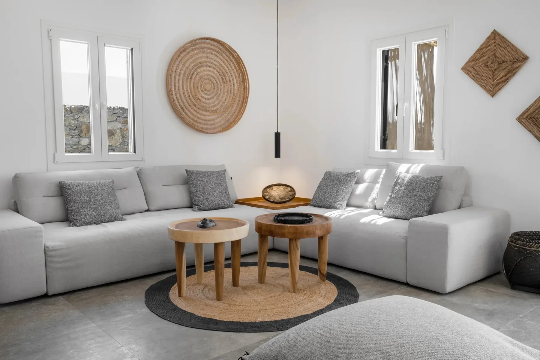 A bright living room with a light-colored sectional and two round coffee tables.