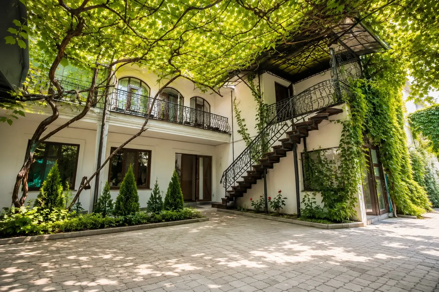 Representative hotel space: A leafy courtyard surrounds a building with an exterior staircase.