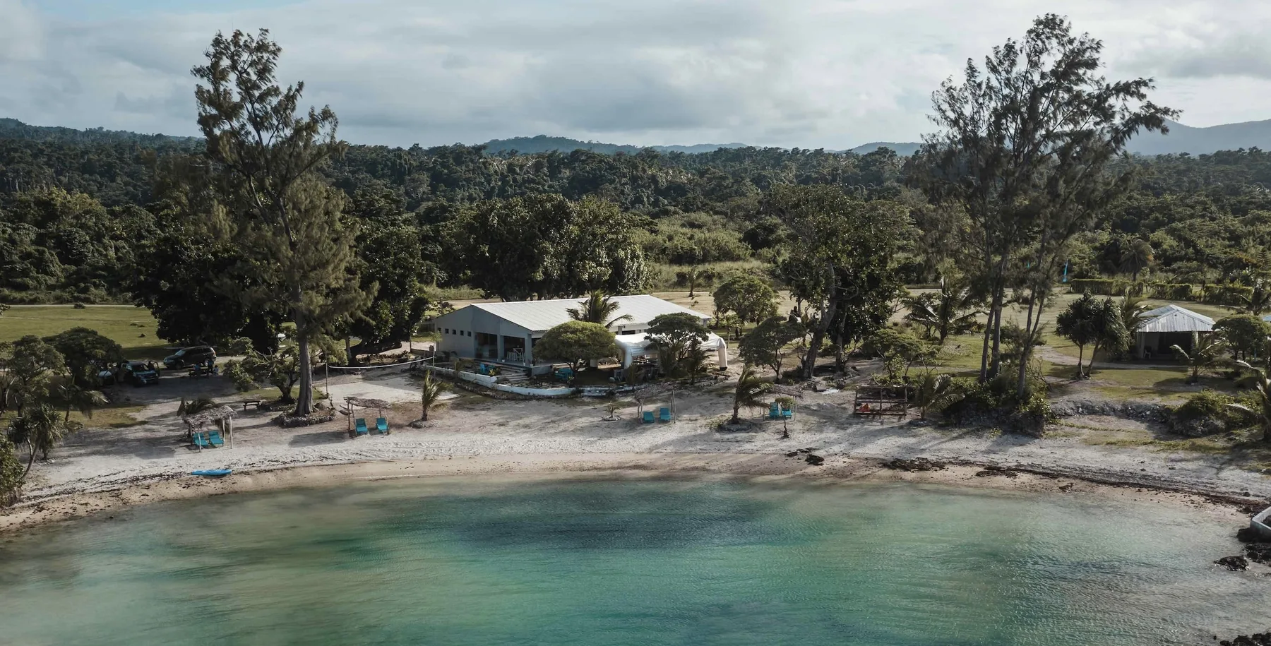 Representative hotel space: Aerial view of a wooded shoreline with buildings beside clear water.
