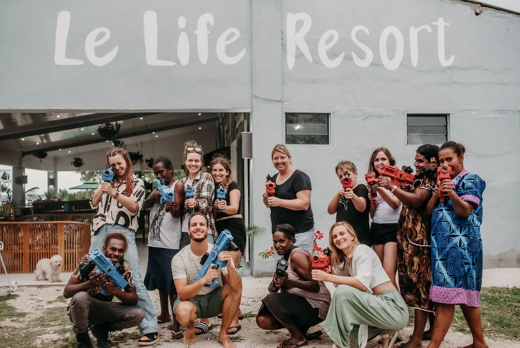 Representative hotel space: A group poses outside a resort entrance beneath a large sign.
