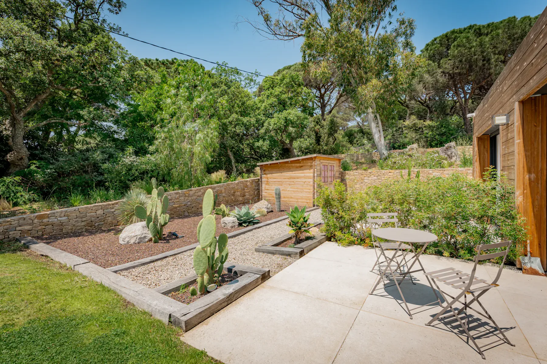 Un patio ajardinado con cactus, parterres y asientos al aire libre.