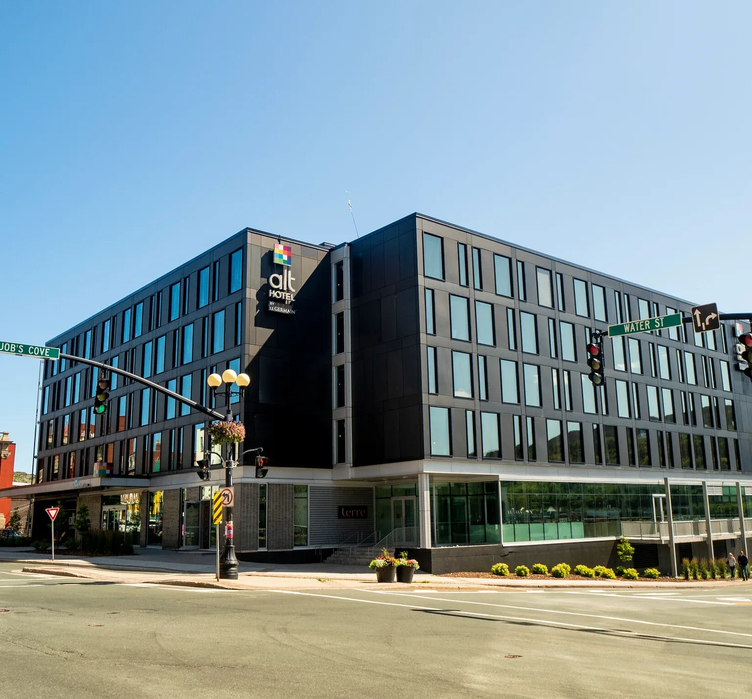 Representative hotel space: A modern hotel building stands on a city street corner beneath a clear sky.