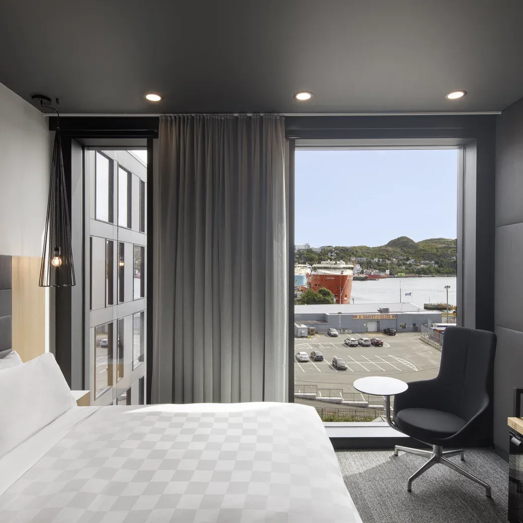 Representative hotel space: A bedroom with a bed and a large window overlooking the water.