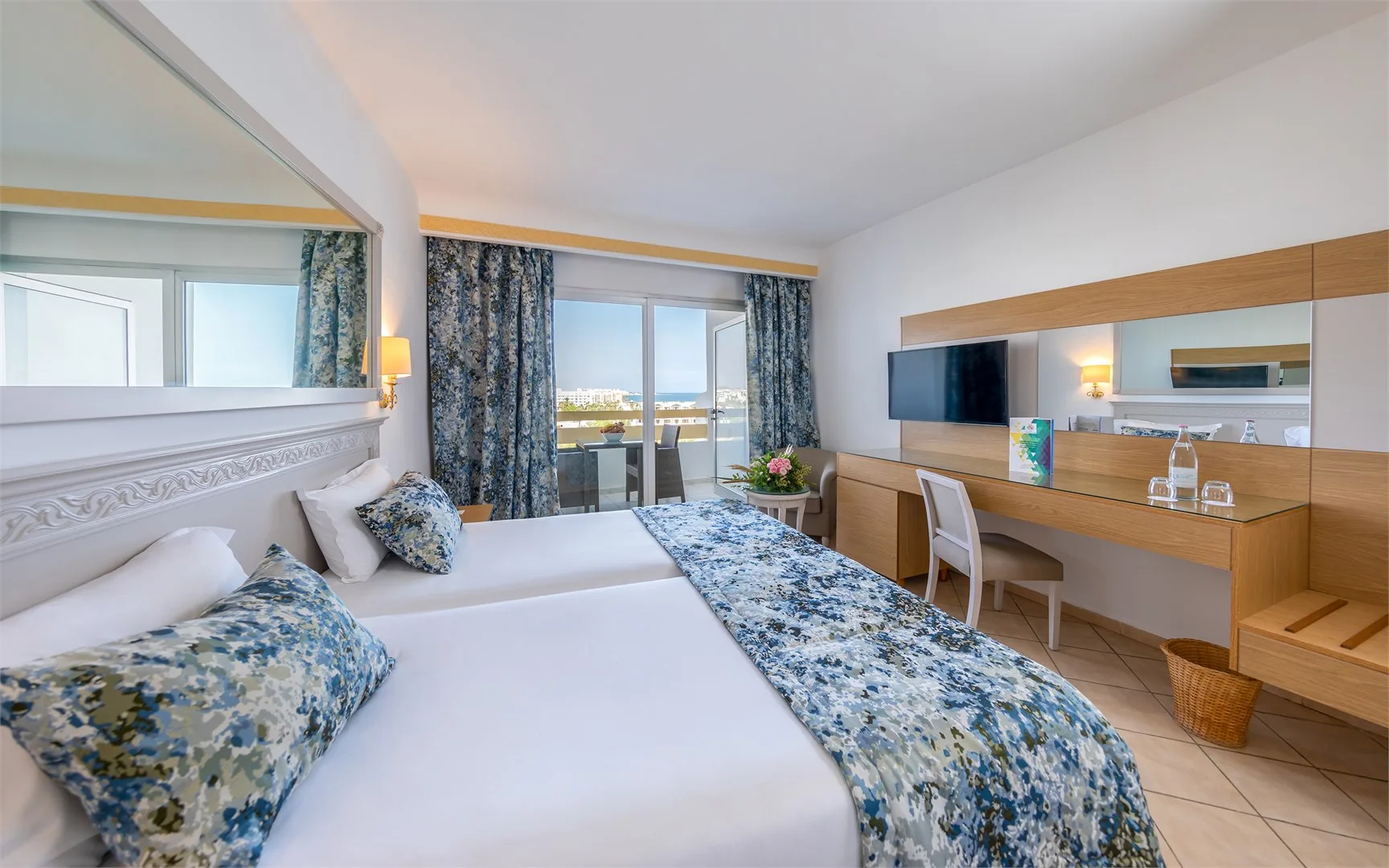 Espacio representativo del hotel: Un dormitorio con una cama, ropa de cama estampada y un escritorio junto a la pared.