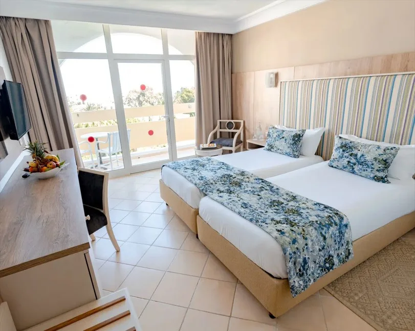 Espacio representativo del hotel: Un dormitorio de hotel luminoso con camas individuales junto a una ventana grande.