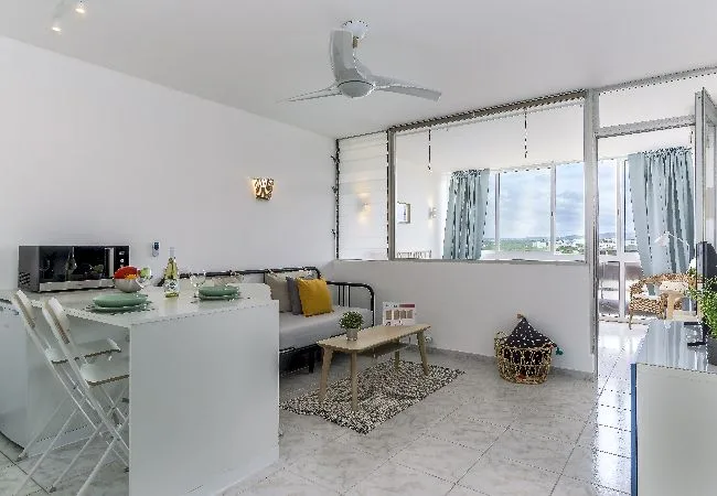 A bright living and dining area with seating, a table, and large windows.