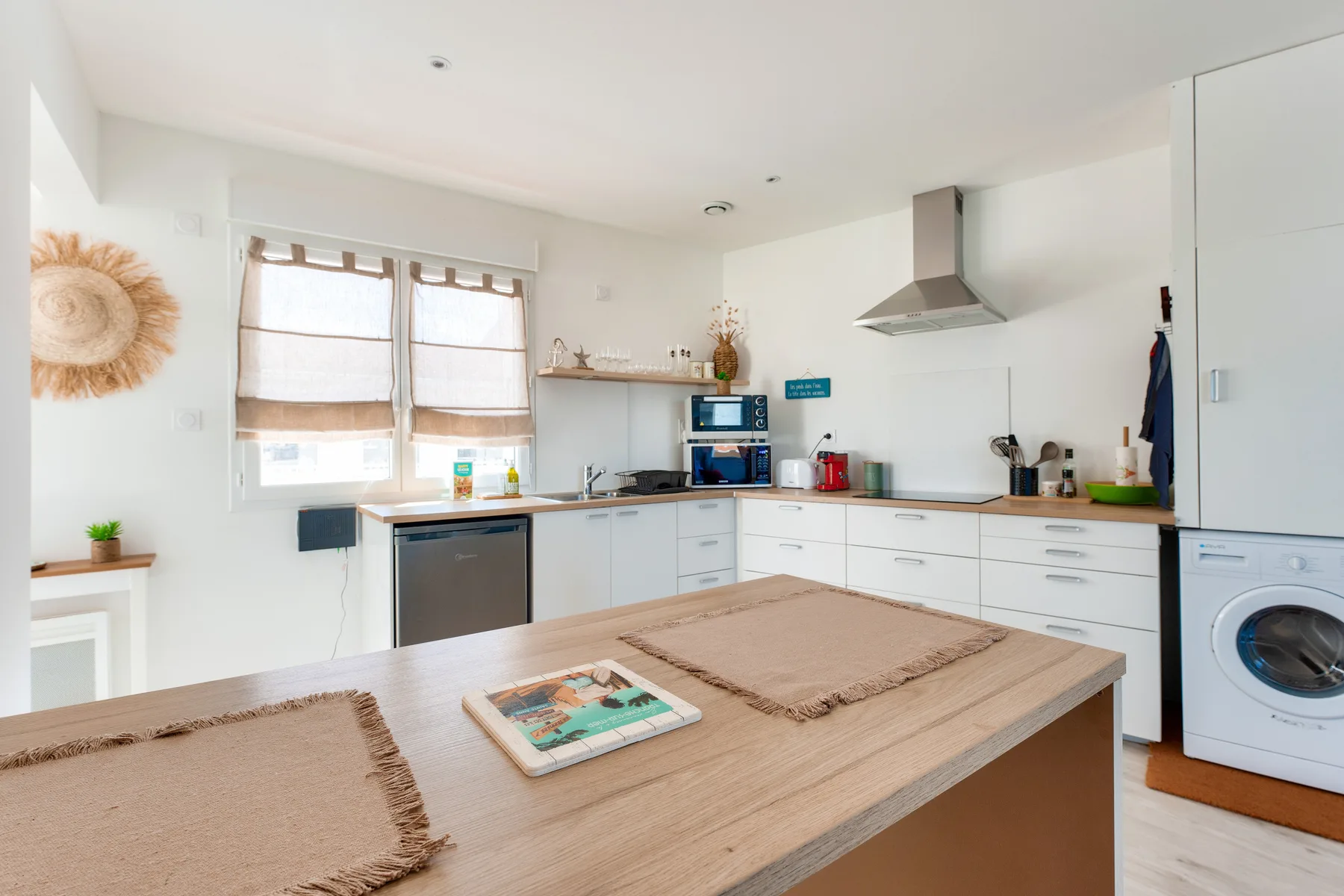 A bright kitchen with a wide wooden island and white cabinets.