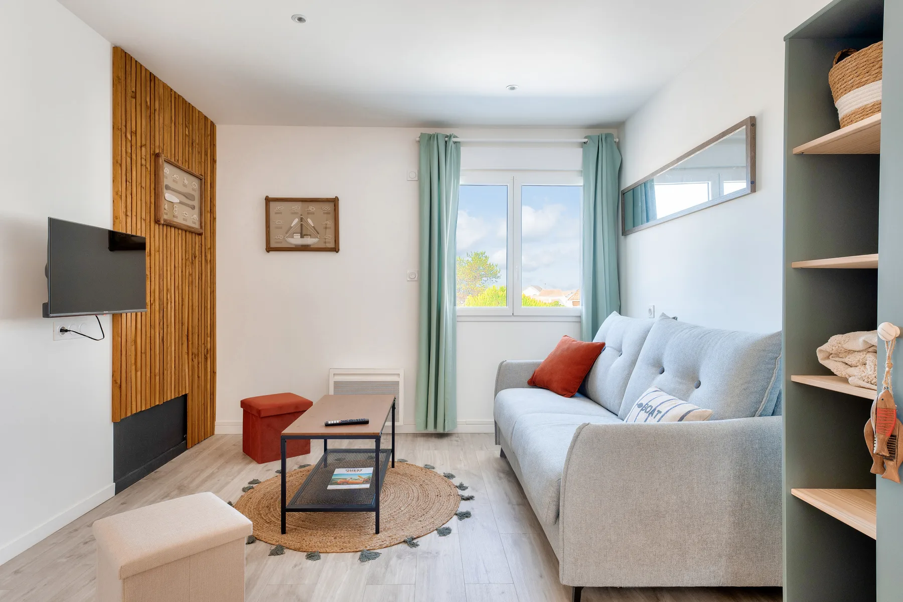 A bright living room with a light-colored sofa beside a window with teal curtains.