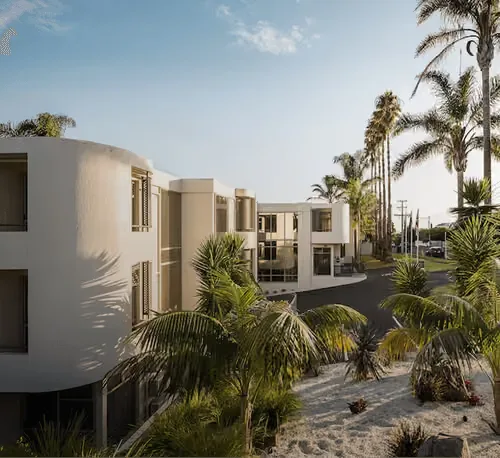 Representative hotel space: A modern low-rise building stands among palm trees and landscaped grounds.