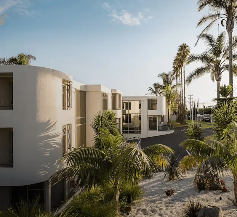 Representative hotel space: Modern low-rise buildings stand among palm trees and tropical landscaping.