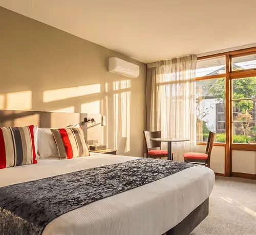 Representative hotel space: A bedroom with a bed and a small table beside a bright window.