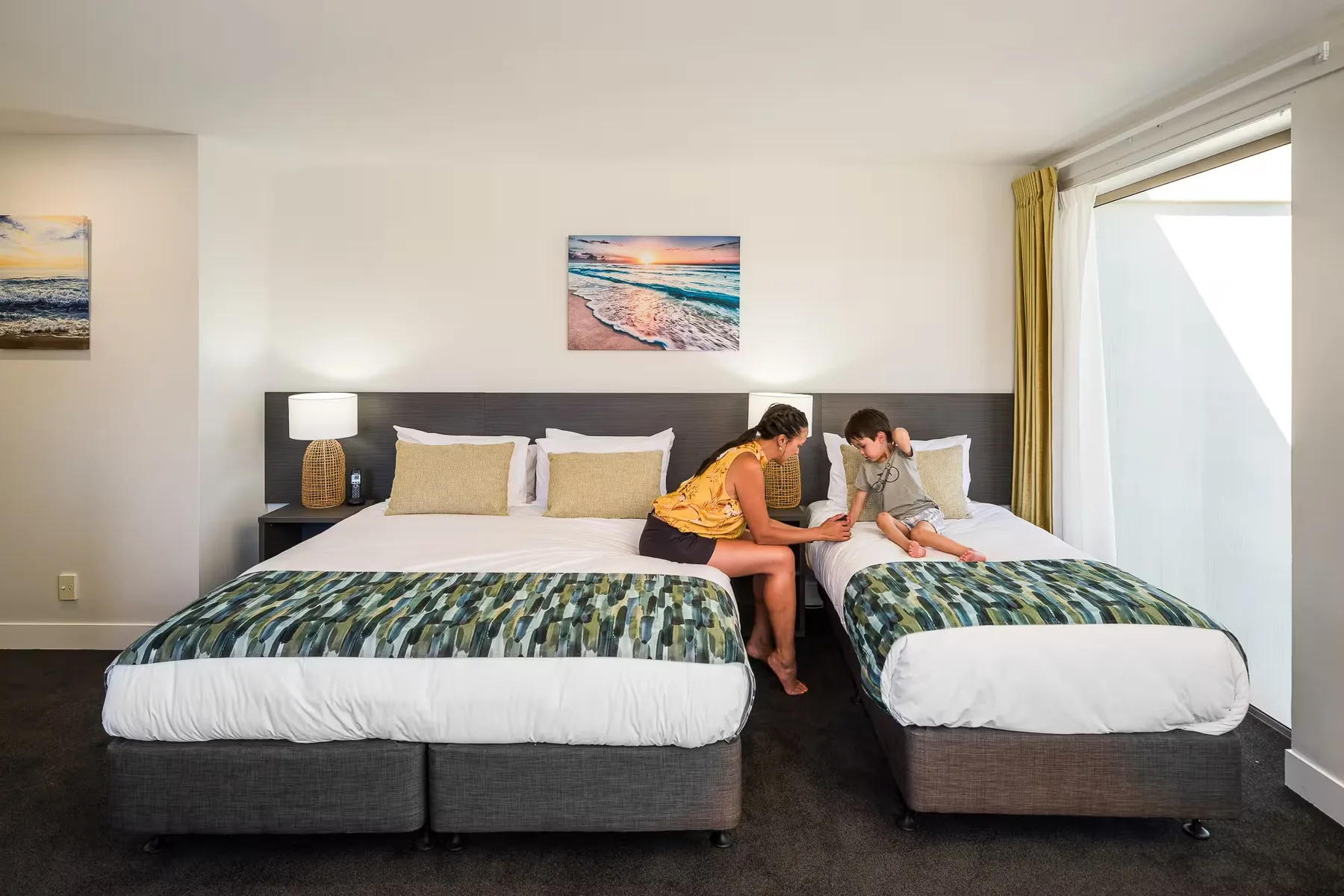 Representative hotel space: A bedroom with two beds and two people sitting together.