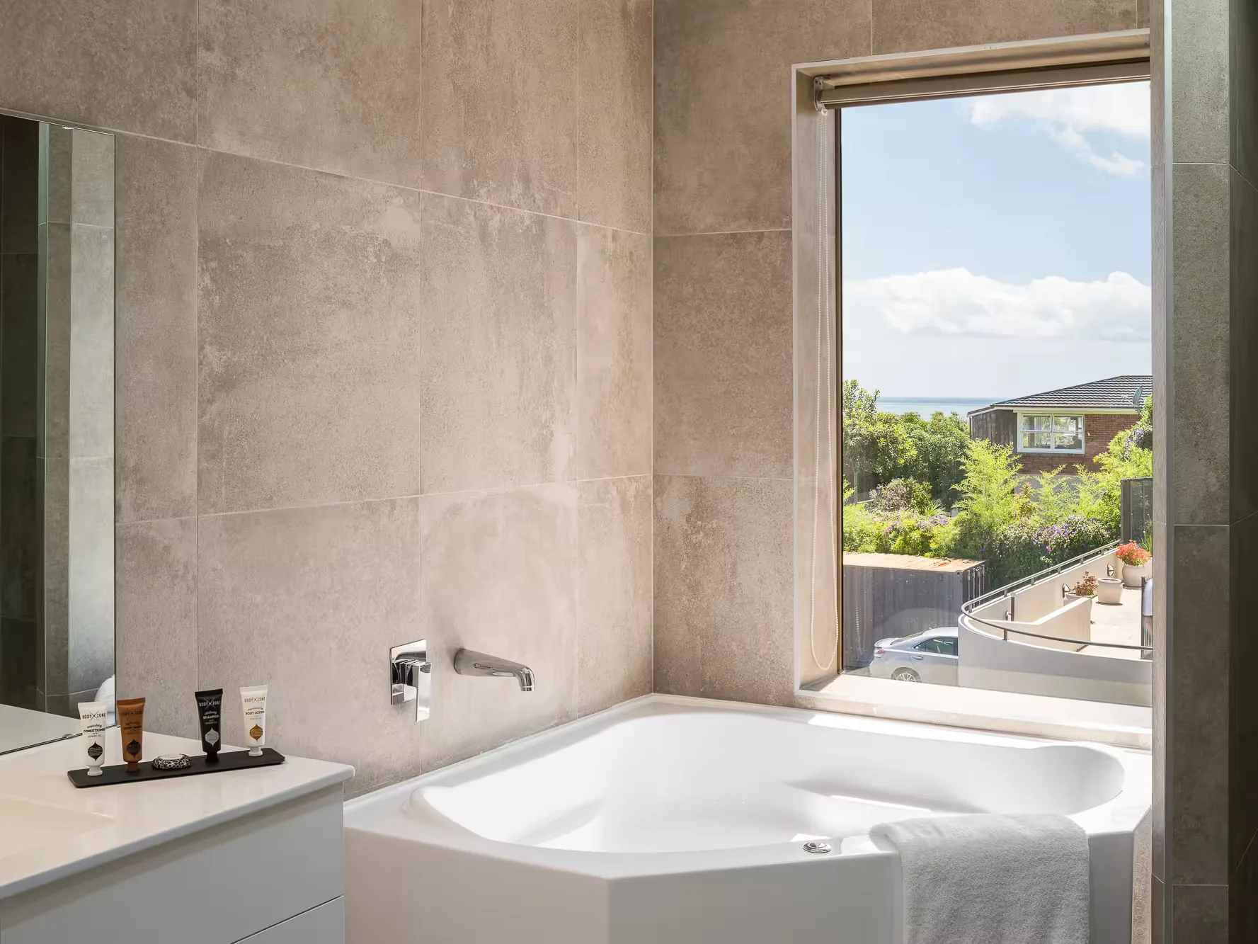Representative hotel space: Bathroom with a bathtub beside a large window overlooking greenery.