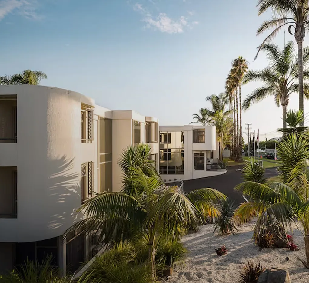 Representative hotel space: Modern building exterior surrounded by palm trees and landscaped greenery.