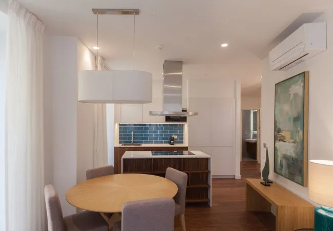 A dining area opens onto a kitchen with blue tile backsplash.