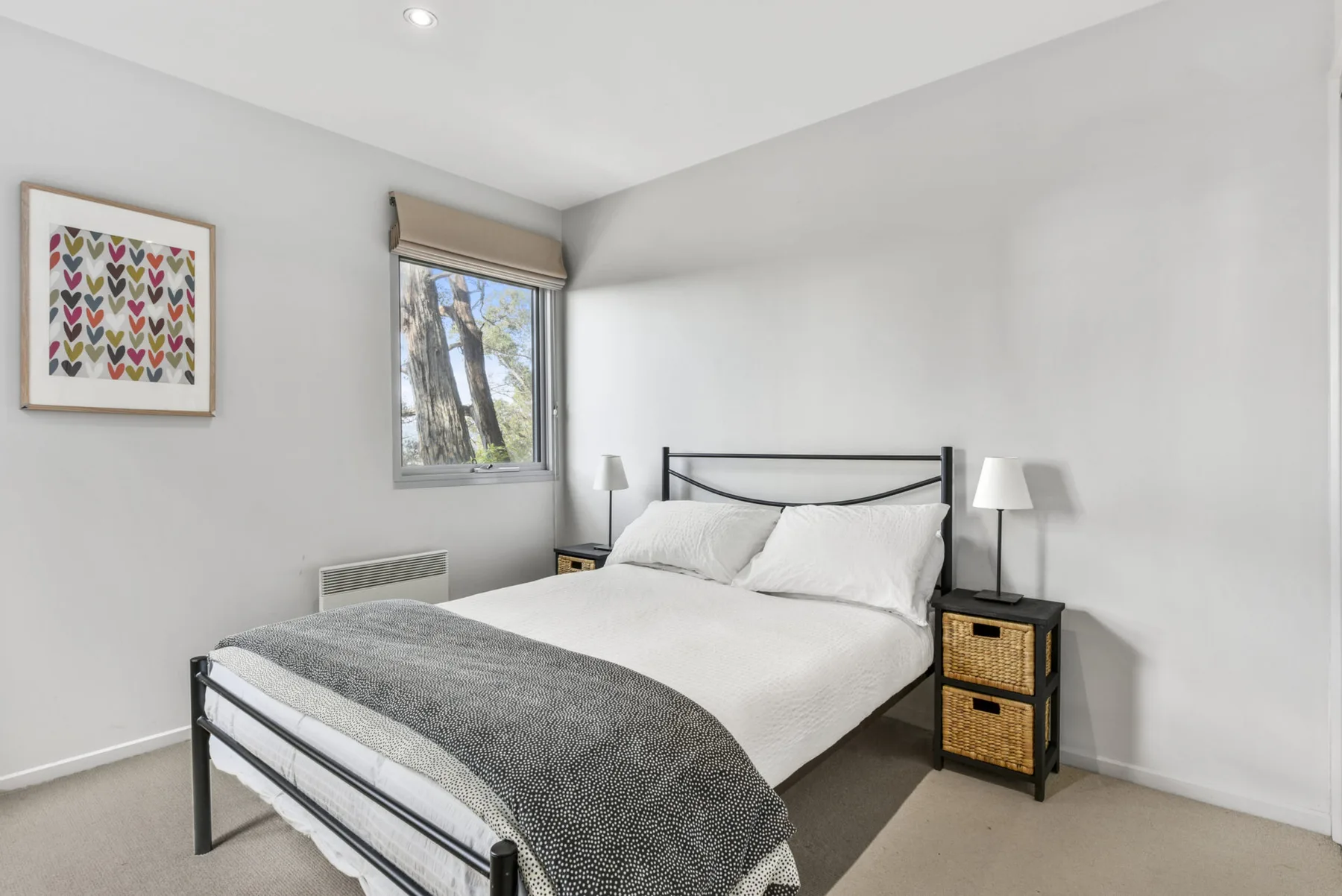 A bright bedroom with a metal bed, white bedding, and a window.