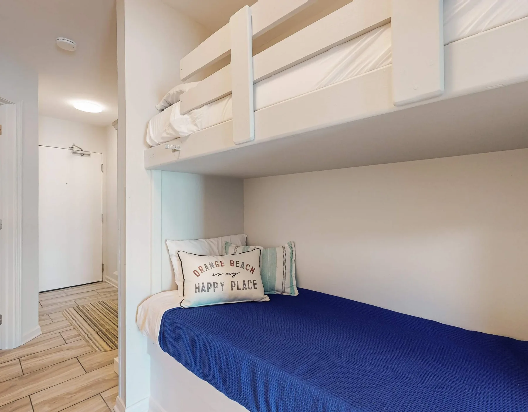 Una litera con la cama inferior cubierta de azul y almohadas en una pequeña zona para dormir.