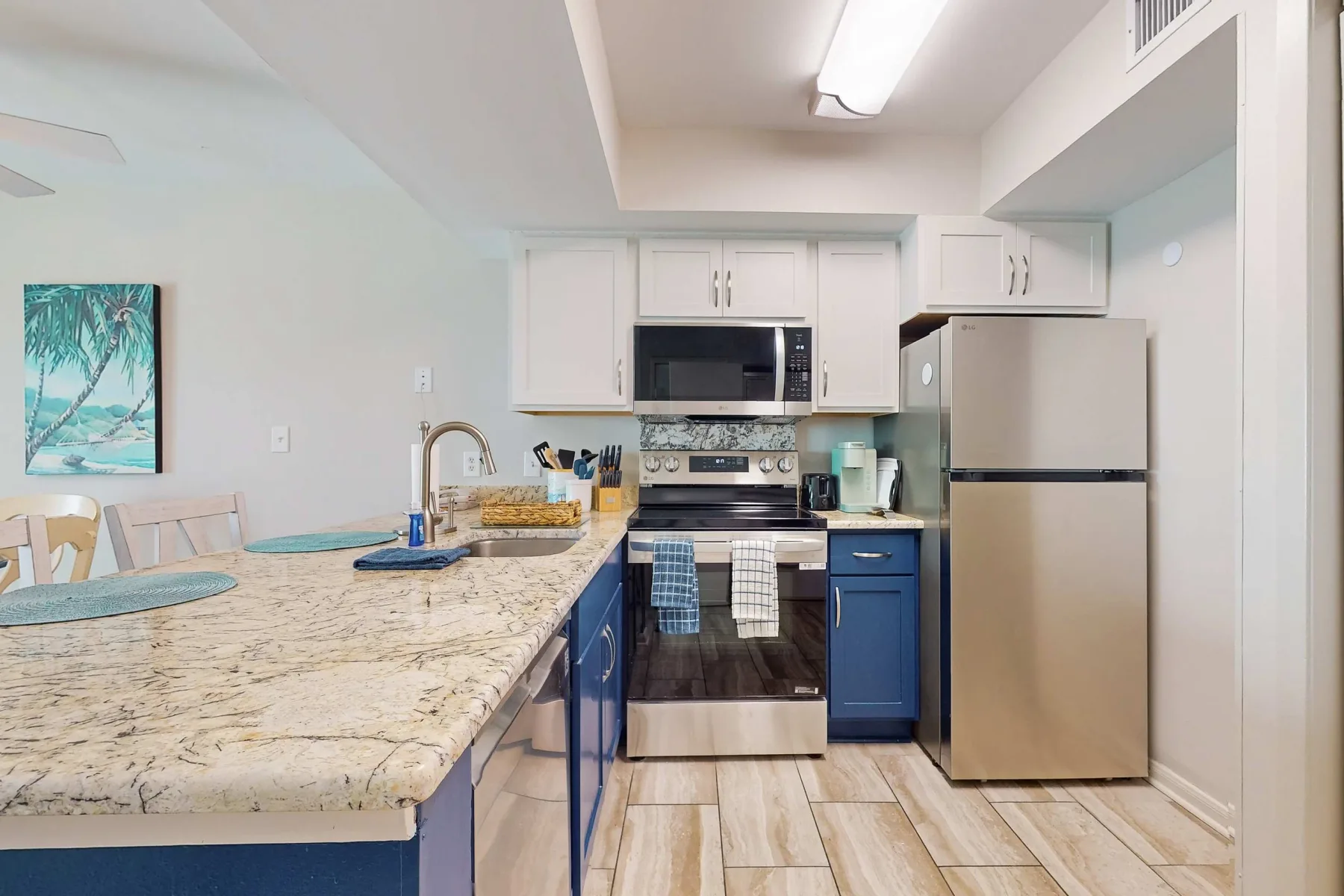 Una cocina con gabinetes azules, encimeras claras y electrodomésticos de acero inoxidable.