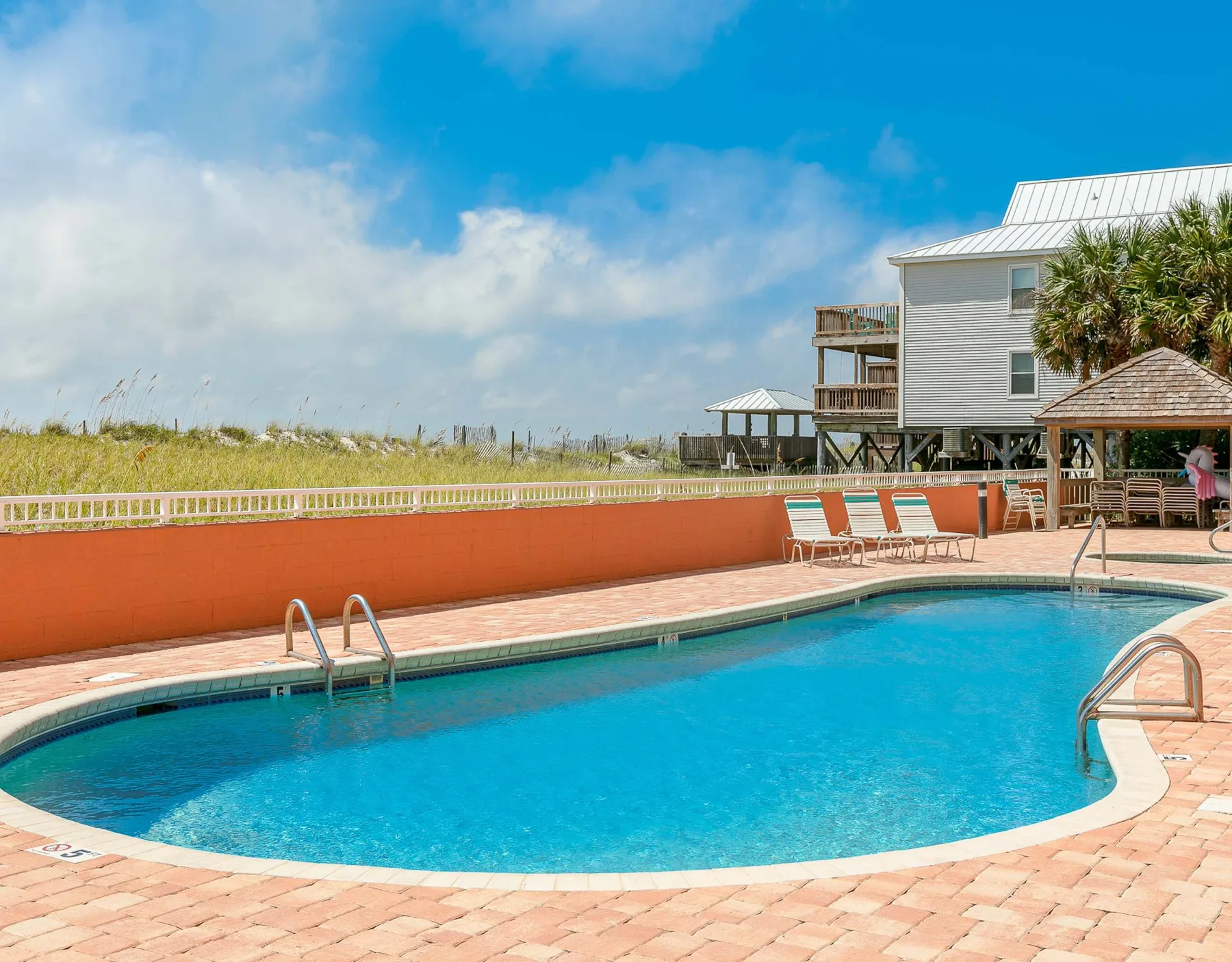 Zona común: Piscina al aire libre junto a un edificio y dunas cubiertas de hierba.