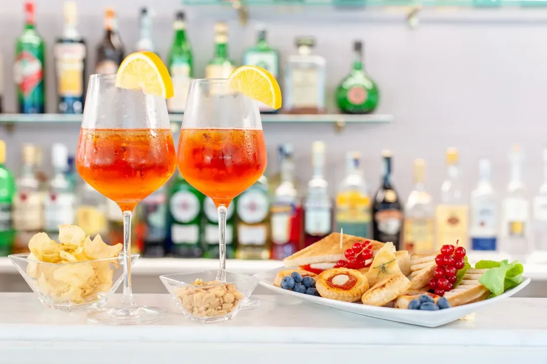 Espacio representativo del hotel: Una barra muestra dos bebidas anaranjadas y un plato con aperitivos variados.