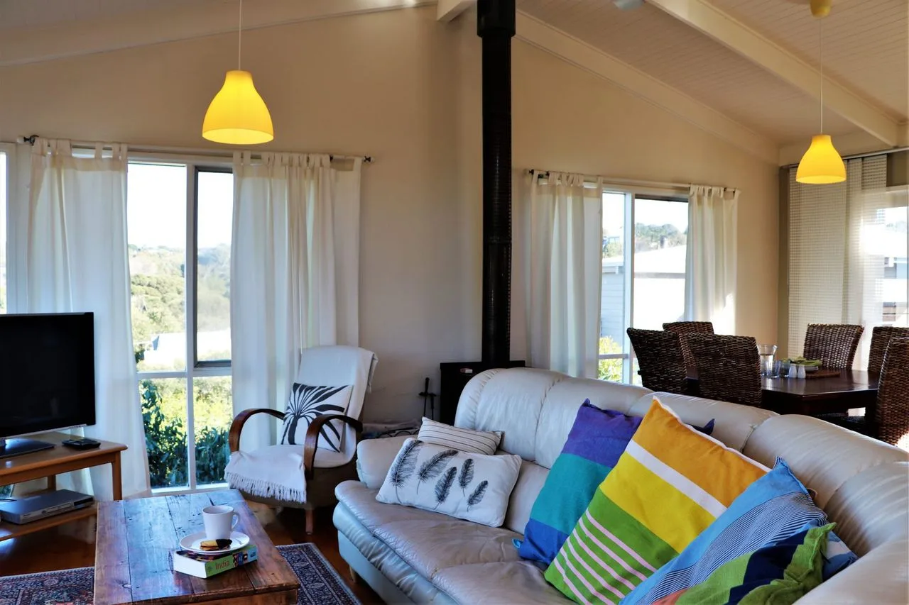 Una sala luminosa con asientos, cojines coloridos y ventanas grandes.
