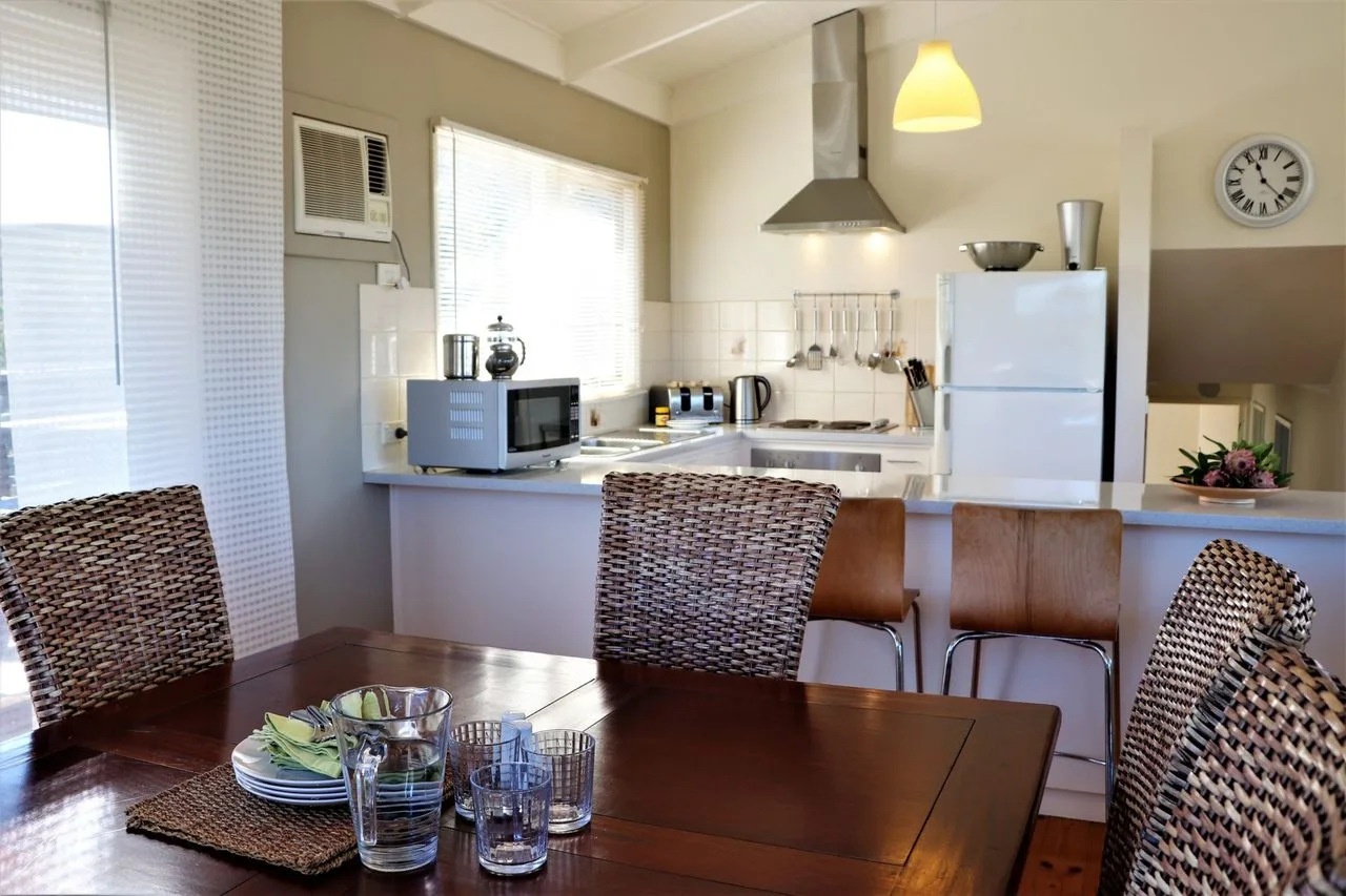 El comedor se abre a una cocina luminosa con una barra y electrodomésticos de acero inoxidable.