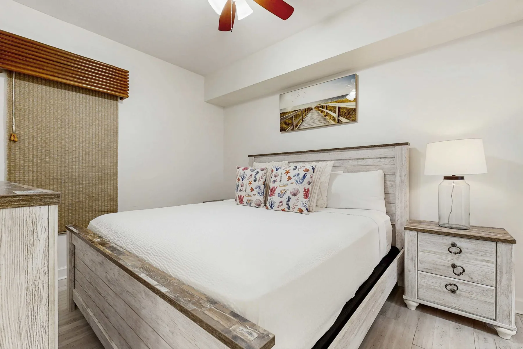 Un dormitorio con una cama, almohadas estampadas y una lámpara de noche.
