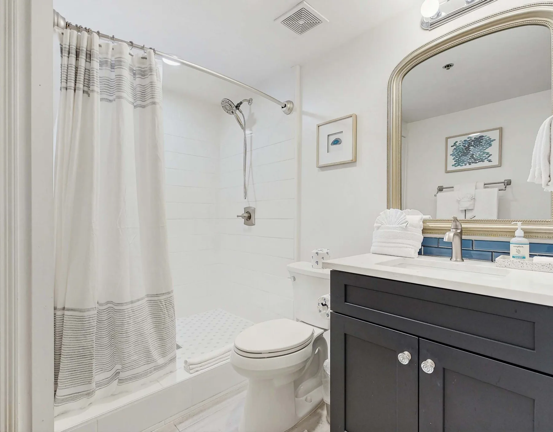 Un baño luminoso con ducha, inodoro y lavabo.