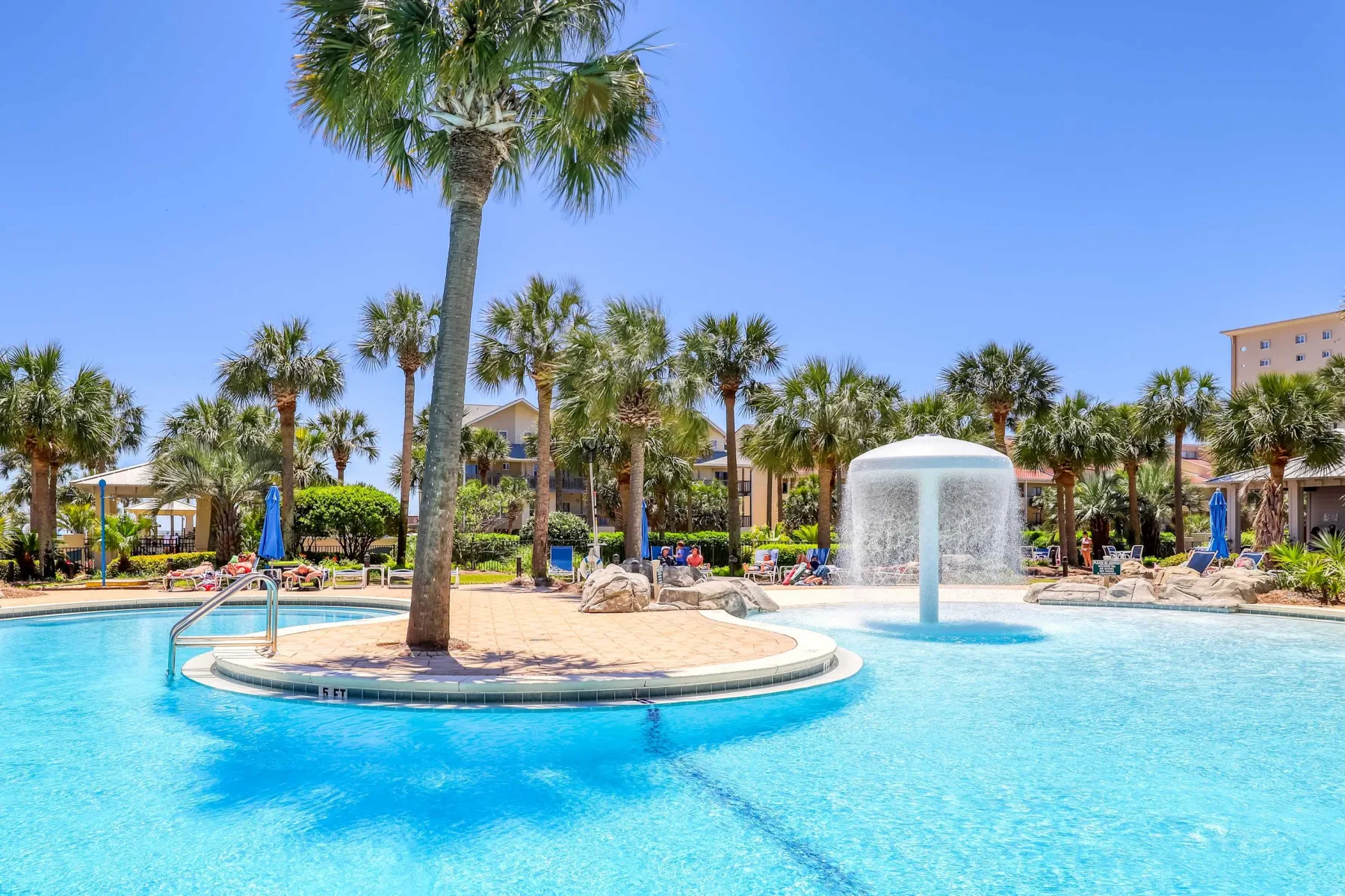 Zona común: Una piscina rodea una pequeña isla con una palmera y una fuente.