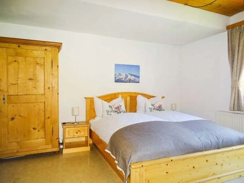 Un dormitorio con una cama de madera, una mesita y un armario.