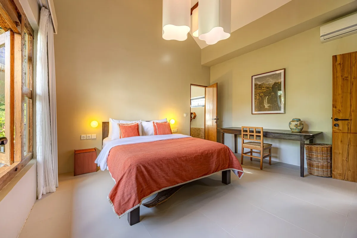 A bedroom with a bed, a desk, and a wooden door.
