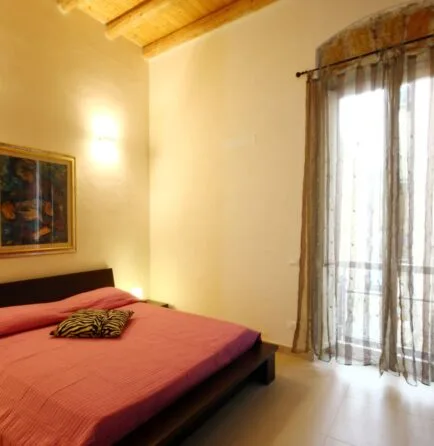 Representative hotel space: A bedroom with a bed beside a tall curtained window.