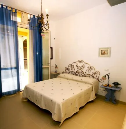 Representative hotel space: A bedroom with a bed, blue curtains, and a small bedside table.