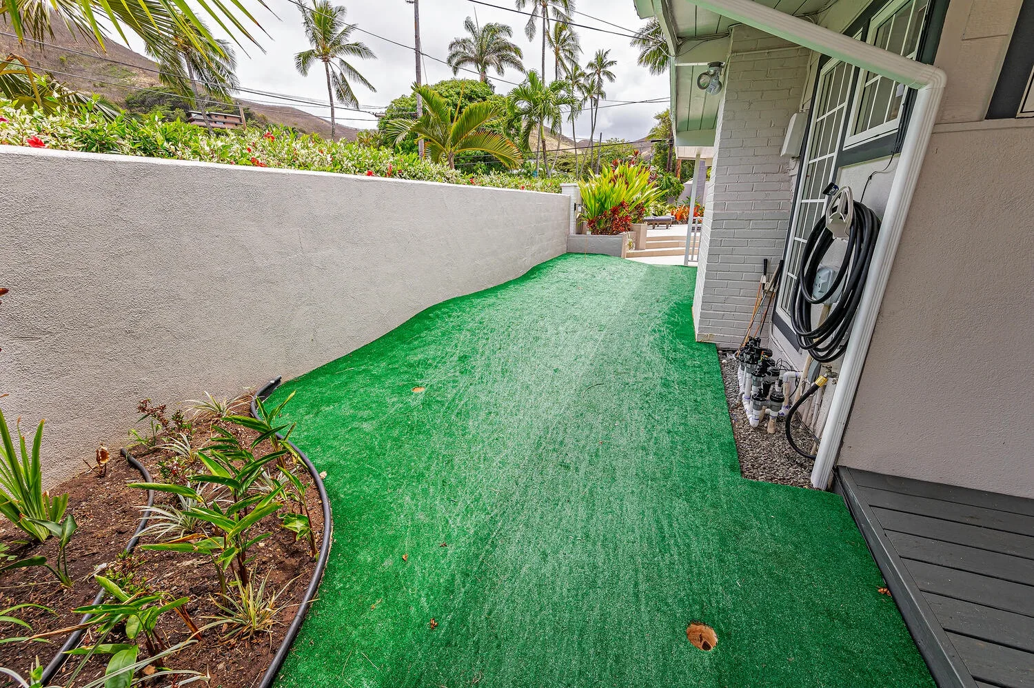 A narrow outdoor walkway covered in green turf runs alongside the building.