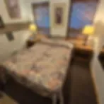Representative hotel space: A bedroom with a bed beside a small table and lamp.