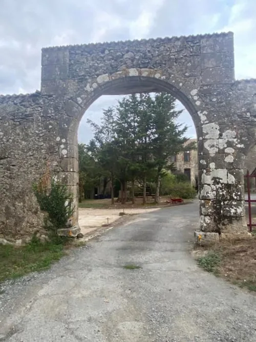 Representative hotel space: A stone archway frames a paved road and trees beyond.
