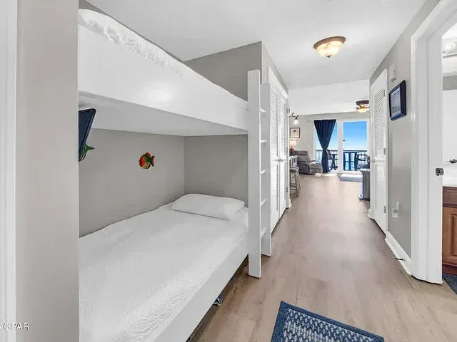 Una zona para dormir con literas da a un pasillo con una sala luminosa al fondo.