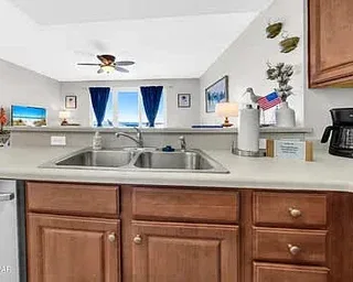 Una encimera de cocina con fregadero, gabinetes de madera y cafetera.