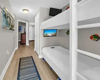 Un dormitorio estrecho con una litera empotrada y un televisor.