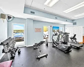 Zona común: Un gimnasio con máquinas de ejercicio y una fila de pesas.