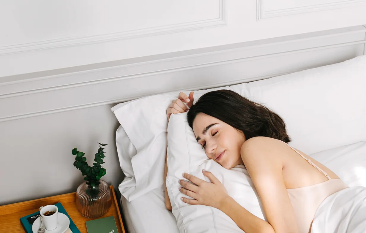 Representative hotel space: A woman rests in bed, hugging a pillow.